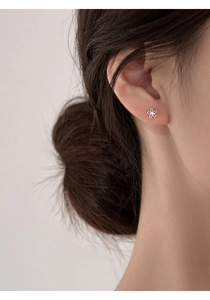 Close-up of minimalist silver flower earring with cubic zirconia worn on model