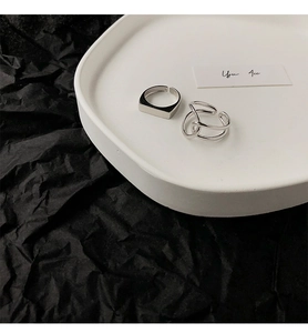 Close-up of minimalist silver open rings with geometric and twisted designs on a tray