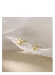 Detail of 925 silver sunflower earrings with gold finish and sparkling zircon center