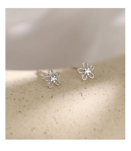 Macro shot of 925 silver flower stud earring with sparkling central zircon on stone