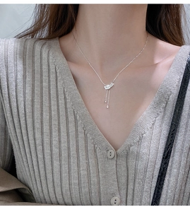 Gros plan du pendentif plume argenté avec cristaux et pampilles porté par un mannequin