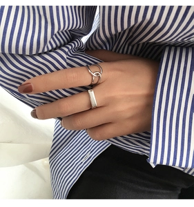 Detailed view of silver knot ring and rectangular band worn for minimalist style