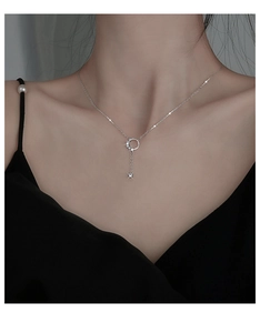 Detail of silver crescent moon and star tassel necklace on model in black dress