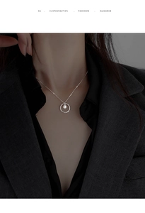 Detail of silver pearl circle pendant necklace on model with grey blazer