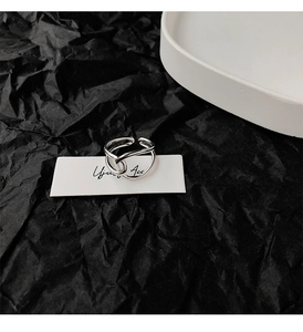 Detail of silver twisted geometric open ring on a minimalist jewelry display card