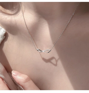 Detail of Mobius infinity necklace with crystals showing artistic shadow on collarbone
