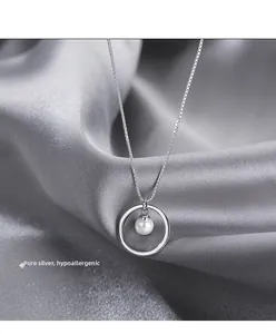 Detailed close-up of sterling silver ring pendant with pearl on silk background