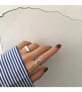 Detail view of silver geometric open rings on a model hand with minimalist industrial style