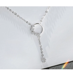 Detailed close-up of a silver circle necklace featuring cubic zirconia and star tassel