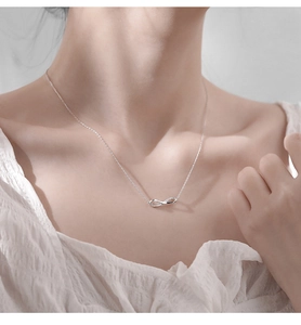 Close-up of silver infinity necklace with micro-pave stones on a minimalist neck chain