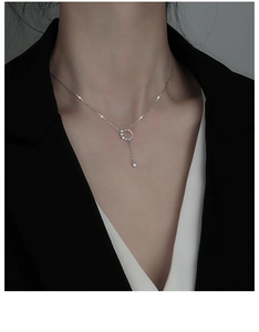 Close-up of a silver circle tassel necklace with zircon stones on a model wearing black