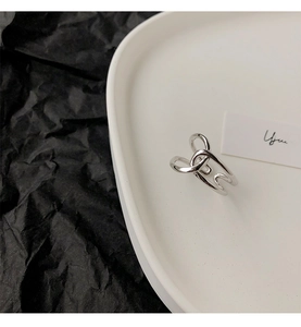 Macro shot of silver-tone intertwined geometric open ring on minimalist tray
