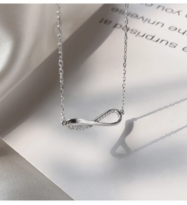 Macro shot of silver infinity necklace pendant with sparkling cubic zirconia on white satin