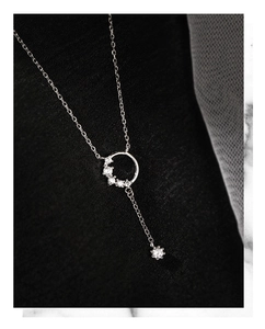 Macro shot of silver tassel circle necklace with sparkling cubic zirconia on black fabric