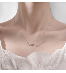 Close-up of elegant silver infinity necklace with zircon accents on a model