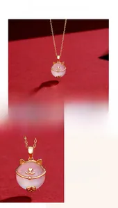 Macro shot of 925 silver cat pendant with pink chalcedony stone and gold details