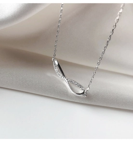 Macro shot of infinity pendant with cubic zirconia pave setting on silver cross chain