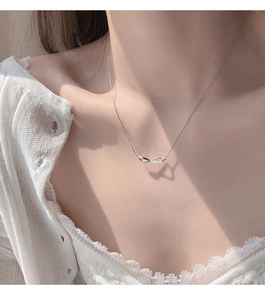 Close-up of infinity pendant with small diamonds on an elegant silver necklace chain