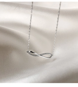 Macro detail of silver infinity pendant necklace with pavé-set sparkling zircons