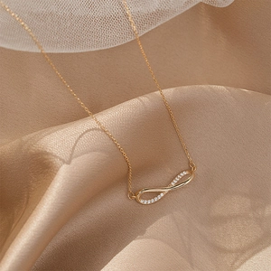 Close-up of gold Mobius necklace pendant with micro-pave zircons on champagne satin