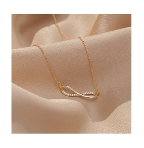 Detail of infinity pendant necklace in gold finish with sparkling white zirconia stones