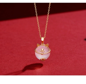 Close-up of golden s925 silver cat pendant with pink chalcedony and gold coin detail