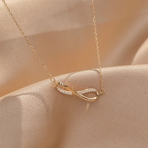 Macro shot of gold infinity necklace with zircons on champagne silk background