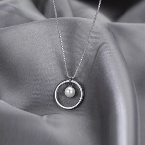 Minimalist silver-toned circle necklace with a lustrous white pearl on a high-end silk backdrop