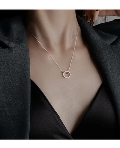 Détail d'un collier pendentif anneau en argent 925 sur un mannequin portant des habits noirs