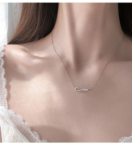 Close-up of infinity pendant silver necklace with sparkling stones on model neck