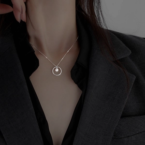 Minimalist silver circle pendant necklace with a white pearl on a black suit model