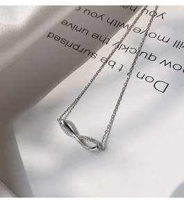 Detail of infinity pendant necklace with cubic zirconia paving on a silver finish chain