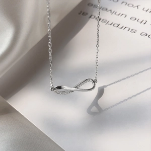 Minimalist silver infinity necklace with sparkling zircon on white silk background