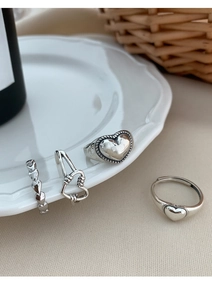 Detail of four retro silver heart rings featuring antique finish and adjustable open bands