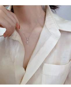Gros plan d'un délicat collier pendentif croix étincelant porté sur une chemise