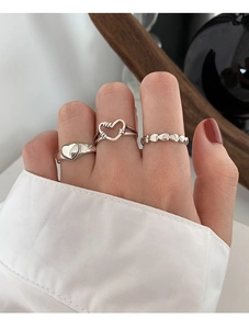 Detailed close-up of a three-piece silver vintage heart ring set on a model's finger