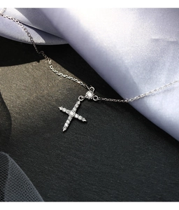 Détail macro du pendentif croix en argent avec connecteur cœur et pavé de zircons brillants