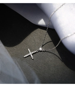 Gros plan d'un pendentif croix en argent avec des zircons brillants sur du satin