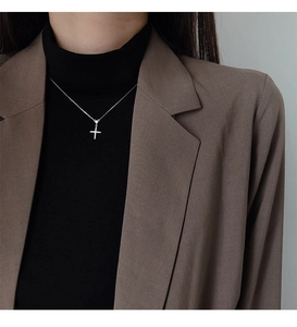 Gros plan d'un collier croix en argent scintillant porté sur un col roulé noir