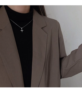 Gros plan d'un collier croix en argent avec oxydes de zirconium sur col roulé noir