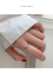 Detail shot of heart-shaped link pattern on silver minimalist ring worn by a model