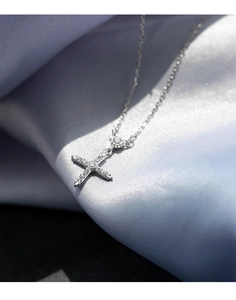 Gros plan du pendentif croix en argent avec zircons brillants sur soie bleue