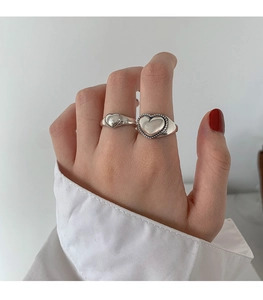 Detail of silver heart-shaped vintage open rings worn with minimalist white outfit