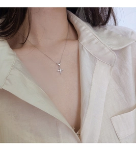 Gros plan d'un élégant collier croix en argent serti de zircons porté par un modèle