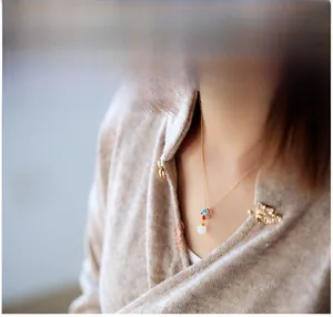 Dettaglio della collana placcata oro con pendente in smalto blu e rosso e perla di giada