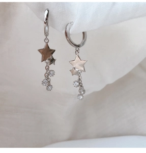 Vue rapprochée de créoles étoile en argent avec glands en zircon sur tissu blanc léger
