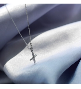 Vue macro du pendentif croix en argent serti de zircons sur fond de soie bleue