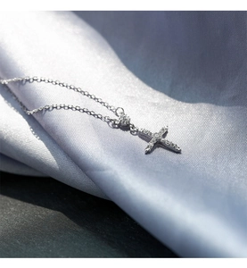 Gros plan d'un pendentif croix argenté avec zircons sur un tissu en satin bleu