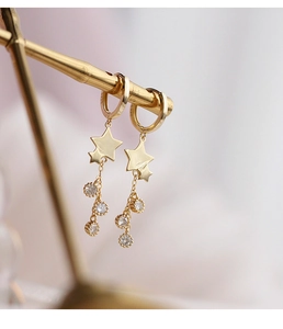 Gros plan de boucles d'oreilles S925 en or avec étoiles et cristaux pendants