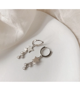 Gros plan des boucles d'oreilles étoile en argent avec franges scintillantes sur soie